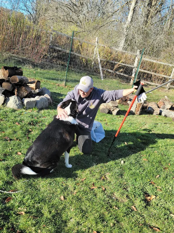 Pawfect Scoop team member with dog during professional dog waste removal service in a fenced backyard